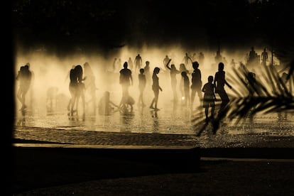 Varias personas se refrescan en la fuente al lado del Río Manzanares en Madrid.