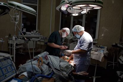 El cirujano plástico austriaco Werner Girsch, a la derecha de la imagen, durante una operación para reconstruir la pierna de un paciente en el hospital militar de Kiev.