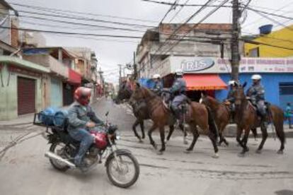 Fotografía tomada en noviembre de 2012 en la que se registró a varios policías y transeúntes al recorrer una de las calles de la favela de Paraisópolis, en Sao Paulo (Brasil). EFE/Archivo