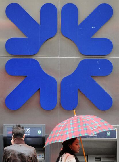Dos personas, delante de la marca de Royal Bank of Scotland en Londres
