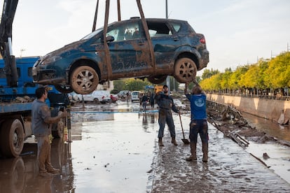 Los vecinos de Utiel retiran un coche afectado por las inundaciones, este jueves.