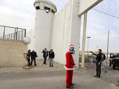 Un manifestante disfrazado de Pap&aacute; Noel, ante el muro de separaci&oacute;n en Bel&eacute;n.