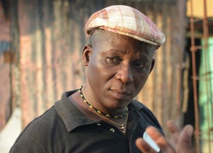 In this April 4, 2016 photo sculptor Andre Eugene speaks to a friend outside his open-air museum and art workshop off a trash-strewn street cutting through some of the poorest neighborhoods in Port-au-Prince, Haiti. He is a founding member of a loose collective of Haitian artists called Atis Rezistans. (AP Photo/David McFadden)