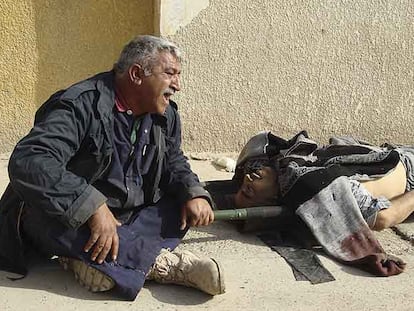 Un hombre llora cerca del cadáver de su hermano, muerto al estallar una bomba.