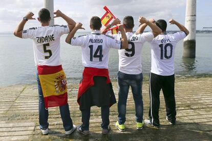 Cuatro aficionados del Real Madrid muestran las camisetas de jugadores del equipo.