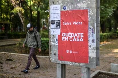 Un hombre camina junto a un cartel de la campaña 'Quédate en casa' del Gobierno de Ciudad de México.