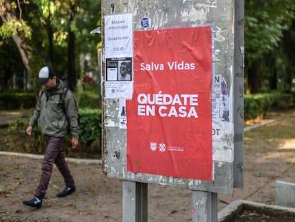 Un hombre camina junto a un cartel de la campaña 'Quédate en casa' del Gobierno de Ciudad de México.