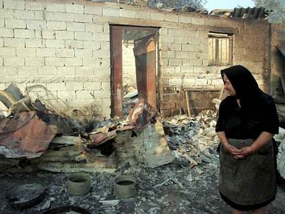 Una anciana observa las ruinas de su vivienda destruida por el fuego en la aldea de Platiana, cercana a Olimpia.