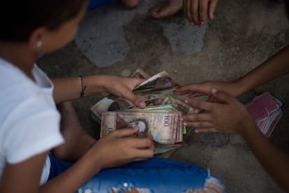 Children play cards and bet with unused Venezuelan bolivar bills