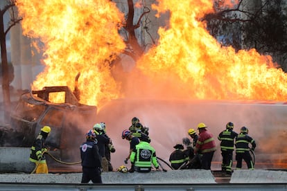 Bomberos intentan apagar el fuego generado por la volcadura de la pipa de gas.