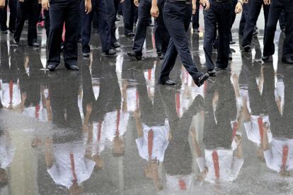 Estudiantes universitarios norcoreanos reflejados en el suelo mojado por la lluvia, mientras esperan el comienzo de un espectáculo de danza en Pyongyang.