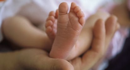 Una madre sostiene a su bebé recién nacido en brazos.