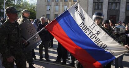 Milicianos prorrusos muestran una bandera rusa frente al edificio regional del Ministerio de Interior, en Lugansk (Ucrania).