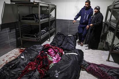 Dos familiares lloran junto a los cadáveres de sus seres queridos muertos en los bombardeos israelíes, este sábado en la morgue del hospital de Jan Yunis.  