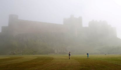 Varias personas juegan al críquet frente al castillo de Bamburgh en Northumberland (Reino Unido).