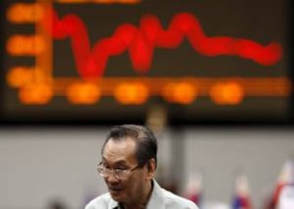 Un corredor de bolsa pasa por delante de un panel electrónico en la Bolsa de Filipinas en el distrito financiero de Makati, Manila. EFE/Archivo