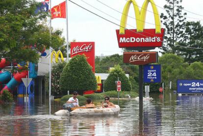 Varios vecinos de la ciudad de Brisbane se trasladan en barca por las inundaciones que han dejado calles y carreteras inutilizables.