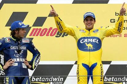 Valentino Rossi observa, brazos en jarras, la felicidad de Alex Barros en el peldaño superior del podio.