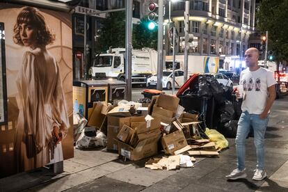 Un hombre pasa delante de varias cajas de cartón junto a los contenedores en la Gran Vía de Madrid, este sábado.