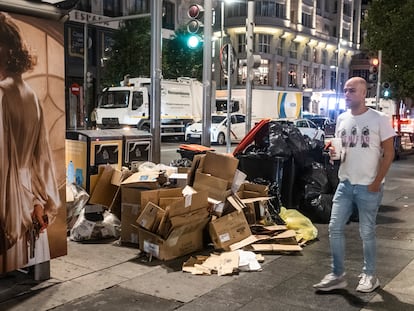 Un hombre pasa delante de varias cajas de cartón junto a los contenedores en la Gran Vía de Madrid, este sábado.