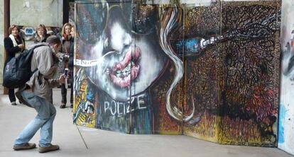 Un asistente fotografía una de las obras de arte urbano en la Neomudéjar.