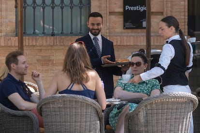 Dos trabajadores en la terraza de un restaurante de Sevilla este jueves, vestidos con mangas largas, pese a las altas temperaturas.