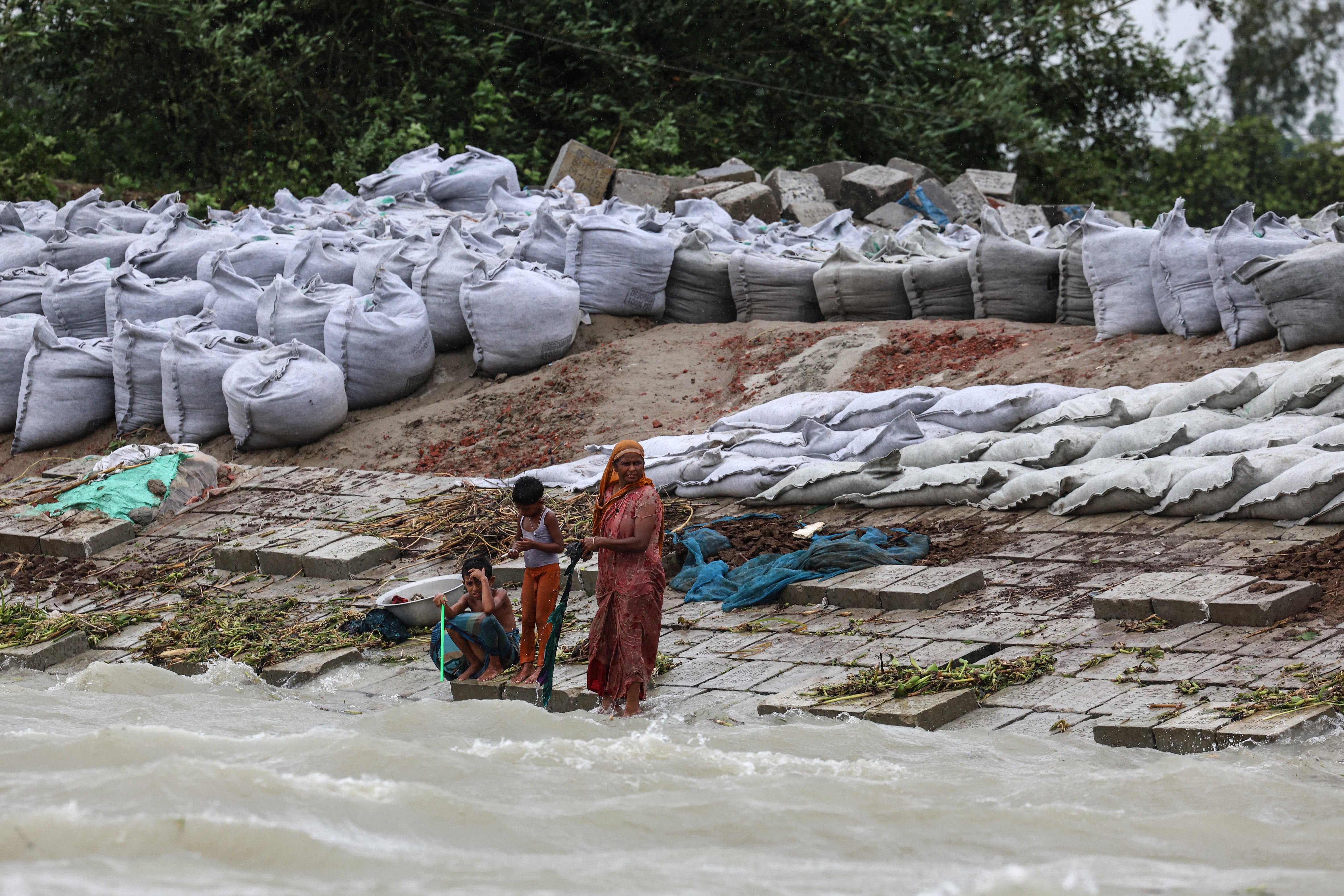 Una mujer y dos niños de pie sobre bloques de cemento que evitan las inundaciones y la erosión en la orilla del río Yamuna en Sirajganj, el pasado mayo.