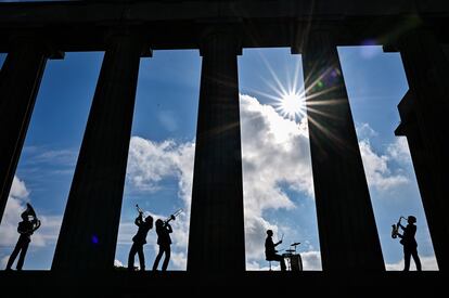 Cinco miembros de la banda Brass Gumbo tocan instrumentos de viento entre las columnas del Monumento Nacional de Calton Hill, en Edimburgo, Escocia.