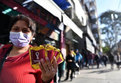 Una mujer muestra los sobres de figuristas que acaba de comprar en un kiosco del barrio de Boedo, en Buenos Aires, el 13 de septiembre de 2022. Detrás, la fila de la gente que esperas su turno.