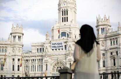 Una mujer observa la pancarta de bienvenida a los refugiados que cuelga de la fachada del Ayuntamiento.