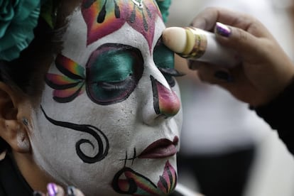 Una mujer repasa su maquillaje para convertirse en una Catrina más durante la celebración en Ciudad de México que congrega cada año a miles de personas.