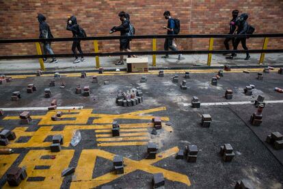 Manifestantes pasan al lado de los adoquines utilizados para bloquear un camino en la Universidad Politécnica de Hong Kong.
