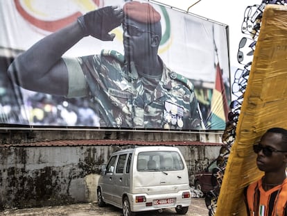 Un vendedor de gafas de sol pasa delante de un gran cartel donde aparece el teniente coronel Mamady Doumbouya, este 11 de septiembre en Conakry.