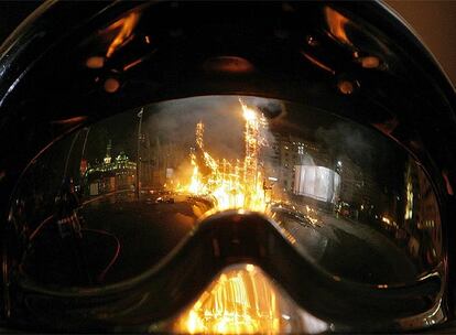 Una falla agonizante se refleja en visera protectora de un bombero. Las fiestas se despiden hasta el año que viene.