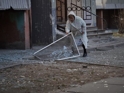 Una mujer recoge los restos de una ventana debajo de su casa, en el edificio atacado el domingo en Kiev.