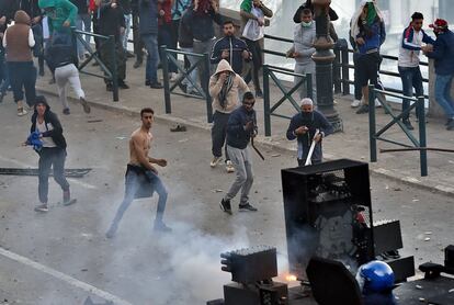 Un grupo de manifestantes se enfrenta a la policía antidisturbios durante los altercados que se han producido con motivo de la multitudinaria protesta contra el presidente Buteflika en Argel.