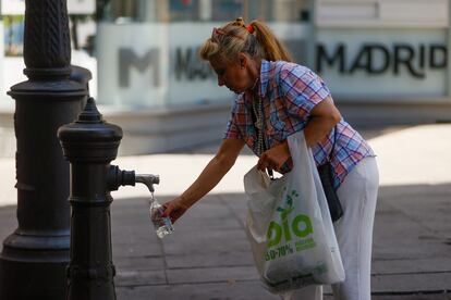 Una mujer rellena una botella de agua en el centro de Madrid, este martes. 
