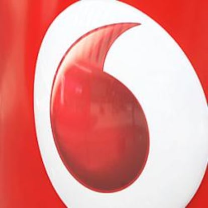 Un hombre habla por el móvil junto a un logo de Vodafone.