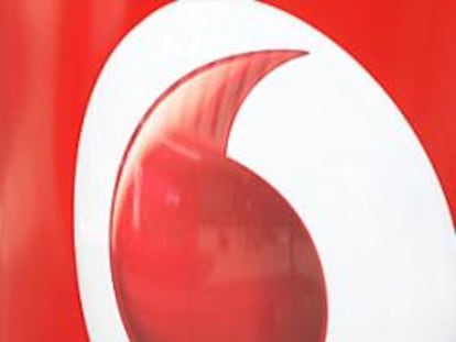 Un hombre habla por el móvil junto a un logo de Vodafone.