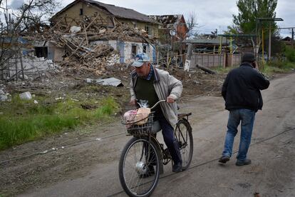 Un residente en la región de Zaporiyia se mueve con su bici entre los restos de casas dañadas tras un ataque ruso el 10 de mayo.