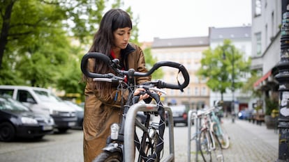 Una chica poniéndole el candado a su bicicleta.