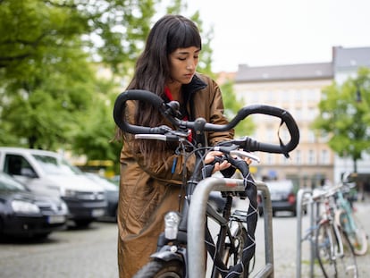 Una chica poniéndole el candado a su bicicleta.