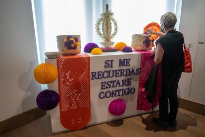 Una mujer dedica a un familiar la ofrenda de en uno de los altares en la Casa de México. 
