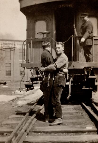Una pareja se abraza, al fondo hay un tren con un ferroviario que les observa. Se desconoce la fecha de la foto, pero sí se sabe que es una imagen estadounidense.