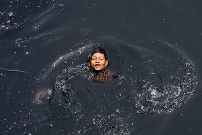 Un niño indio nada en el río contaminado Yamuna en medio del aumento de las temperaturas en Nueva Delhi.