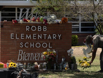 Un oficial coloca flores a las afueras de la Escuela Primaria Robb en Uvalde, Texas después del tiroteo.