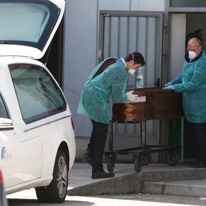 Dos funerarios trasladan un féretro en el hospital Ramón y Cajal.