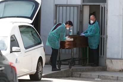 Dos funerarios trasladan un féretro en el hospital Ramón y Cajal.