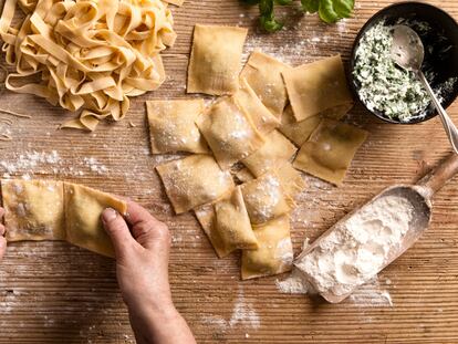 Una mujer prepara diferentes tipos de pasta (espaguetis, tallarines y raviolis) en la cocina de su hogar.