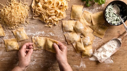 Una mujer prepara diferentes tipos de pasta (espaguetis, tallarines y raviolis) en la cocina de su hogar.